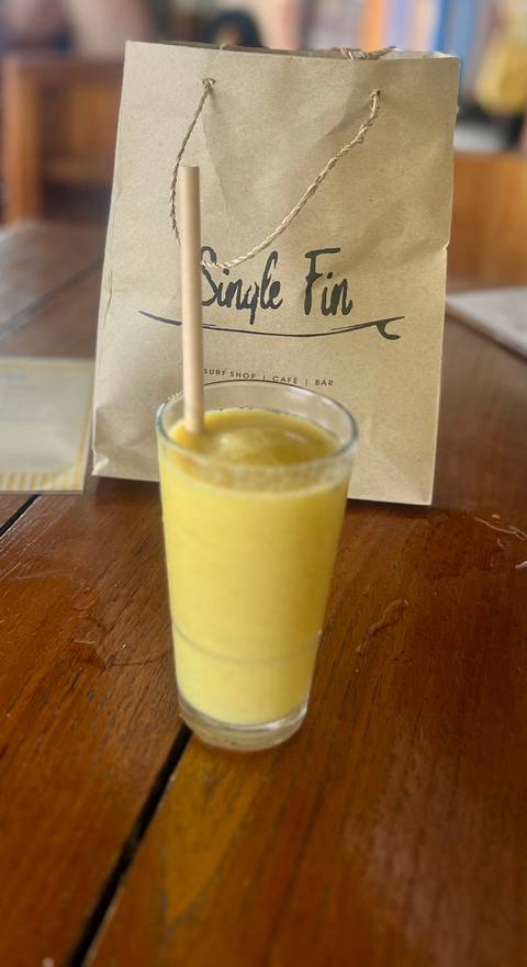 Yellow smoothie in a glass on a wooden table.