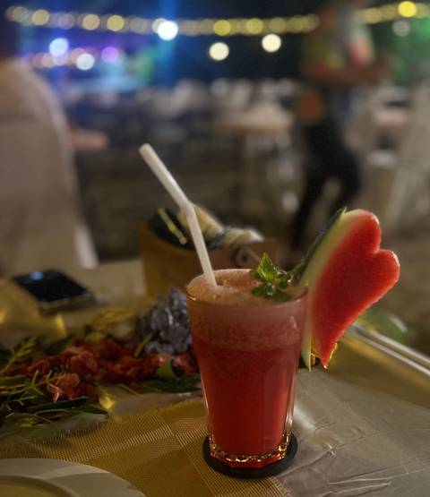 Close-up of a drink with a straw and a watermelon slice garnish.