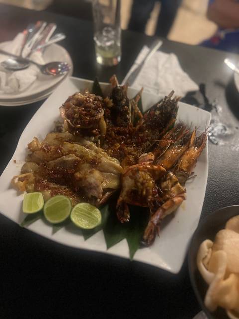       Seafood platter with prawns, fish, and limes on a plate.
  
