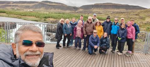 Large group of people posing on a viewing platform in a rocky area.