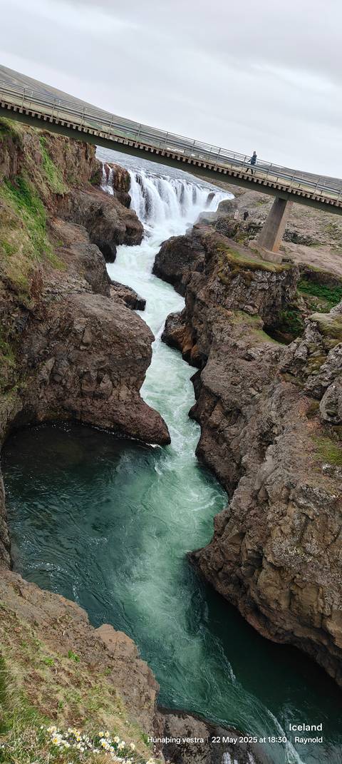 Narrow waterfall flowing through a rocky canyon.