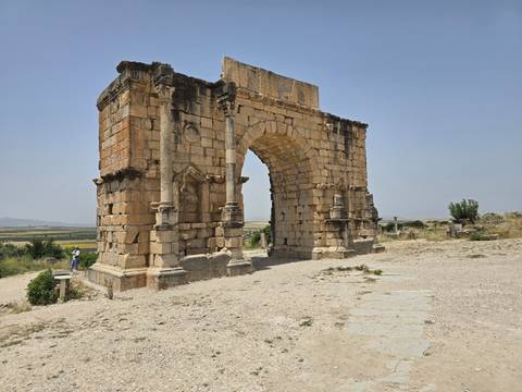 Ancient stone arch in rocky desert landscape.