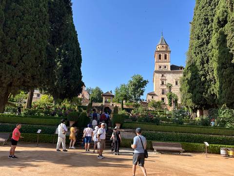 Tourists in a garden with a historic tower in the background.
