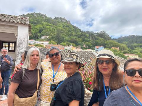 Group of tourists posing with green hills in the background.