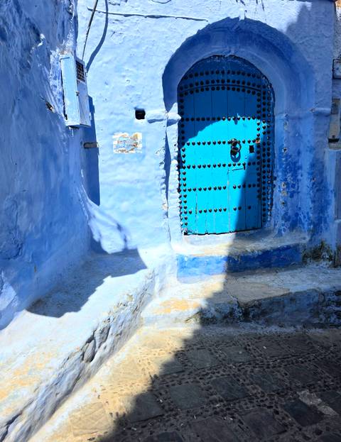Bright blue door on a blue wall in a vibrant alleyway.