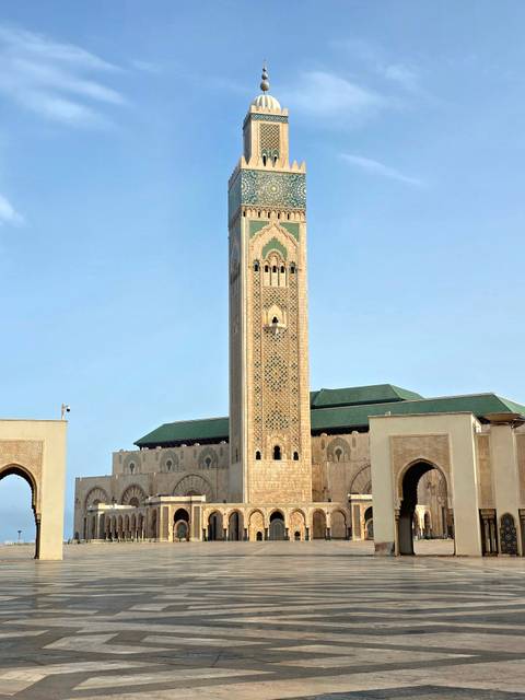 Tall mosque with intricate tile work under a clear sky.