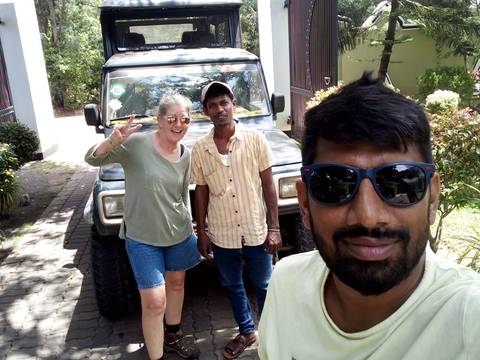 Selfie of three people with a vehicle in the background.