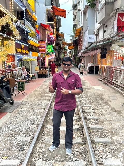 Man standing on train tracks in a vibrant street market.