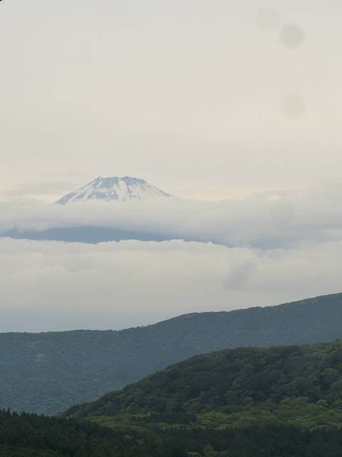 Mount Fuji partially covered by clouds with a clear sky.