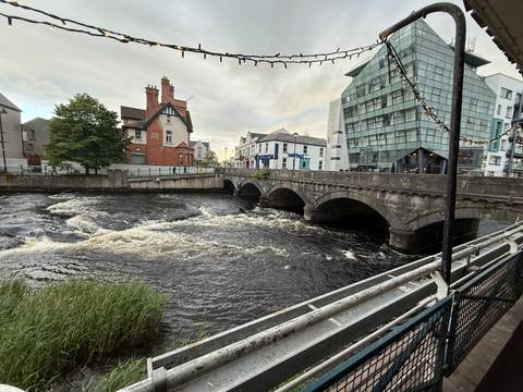 River scene with old and modern buildings and a bridge.