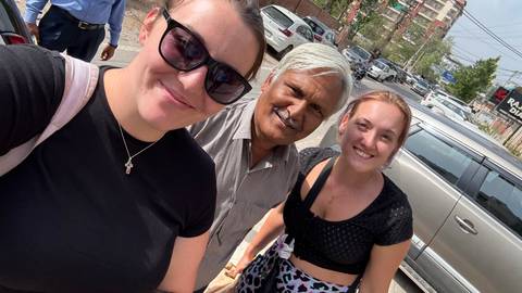       Two women taking a selfie with a local in a street setting.
  