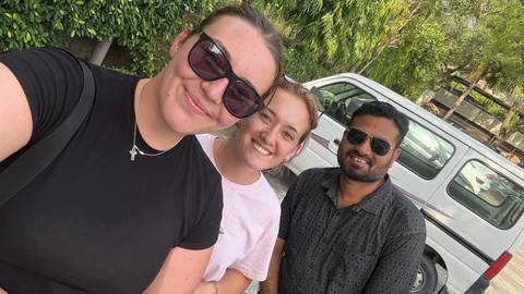       Two women smiling with a local guide, outdoors.
  