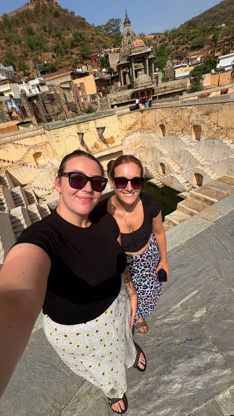 Two women taking a selfie at a stepwell or historic site.