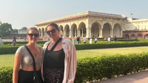       Two women with sunglasses at a historic site with columns.
  