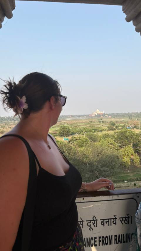 Woman looking at the Taj Mahal from a distance.