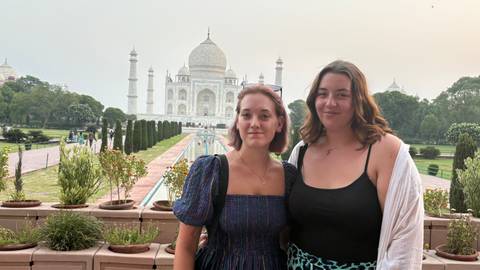       Two women posing in front of the Taj Mahal.
  