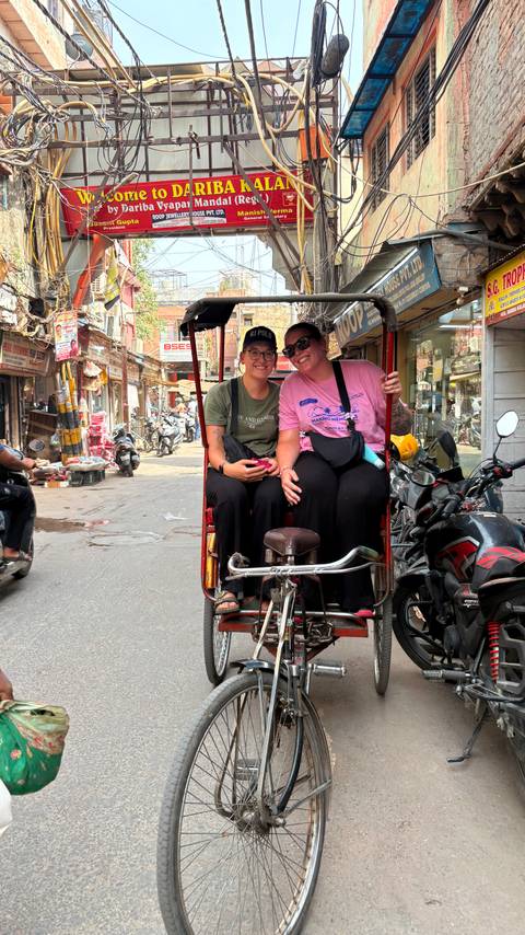       Two women smiling while sitting in a rickshaw.
  