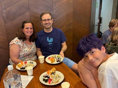       Family enjoying a dinner with sushi and other dishes.
  