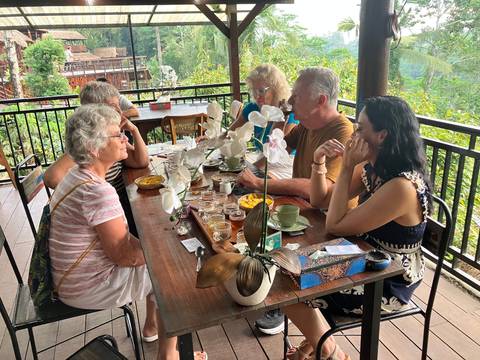 Group of people enjoying drinks and conversation at a scenic outdoor cafe.