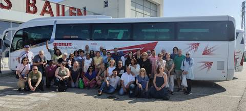       Large tour group posing in front of a bus.
  
