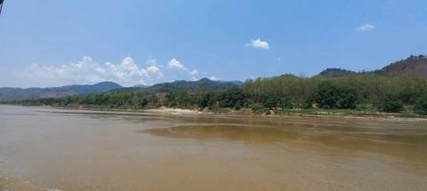       River scene with mountains and trees on a clear day.
  