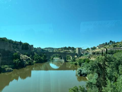 Scenic view of a bridge over a river captured through a bus window.