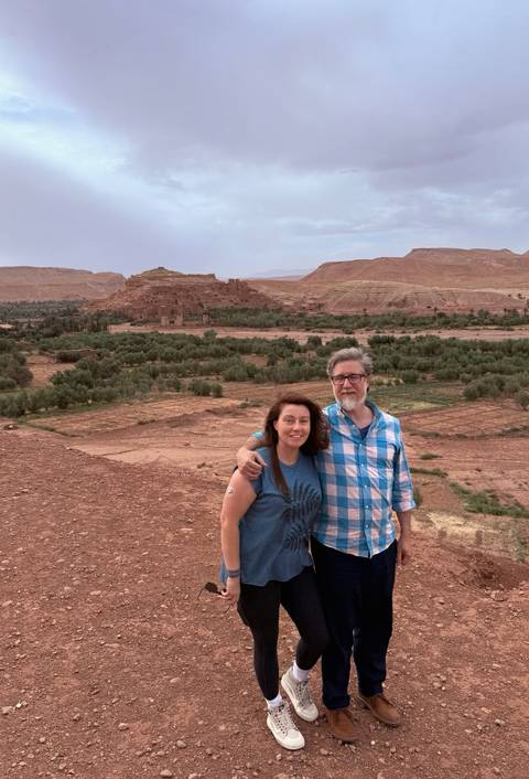 Couple posing in front of a historic site in a lush valley.