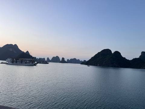 Boats in a bay surrounded by limestone karsts at sunset.