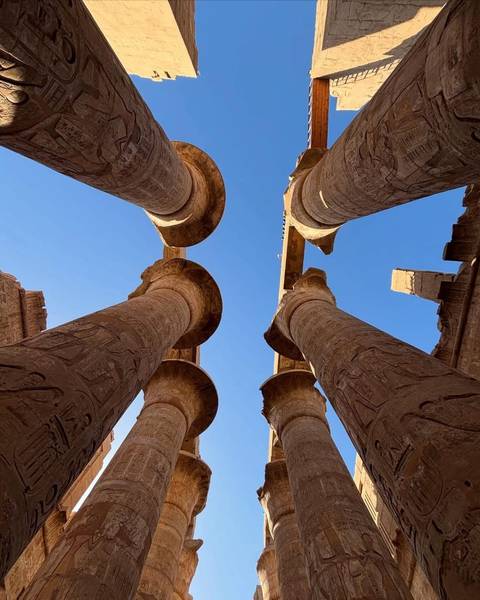 Ancient Egyptian columns with carvings under a clear blue sky.