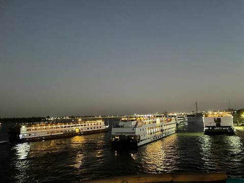 Boats on a river at night with city lights.