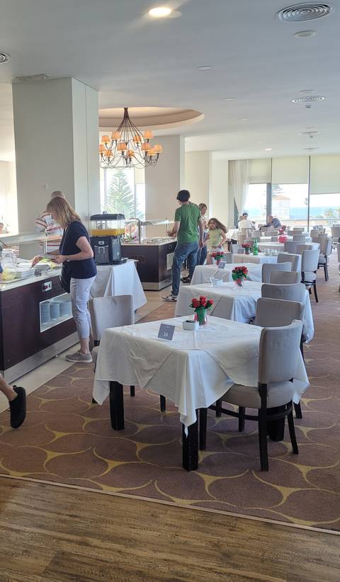 People inside a restaurant with tables set and food station visible.