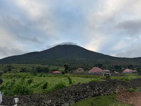 Mountain landscape with houses at the base and clouds overhead.