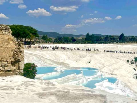 Tourists walking on the terraces of Pamukkale with mineral-rich thermal waters.