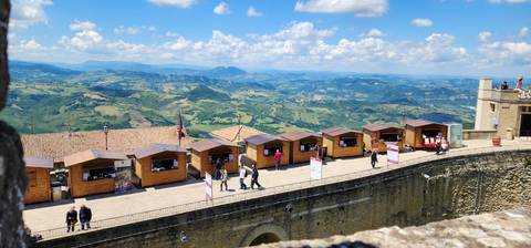       Panoramic view over a hilly landscape with small shops.
  