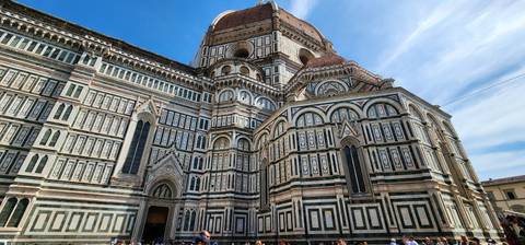       Facade of a grand cathedral with people.
  