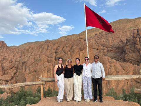Group of people posing with a flag in a rocky landscape.