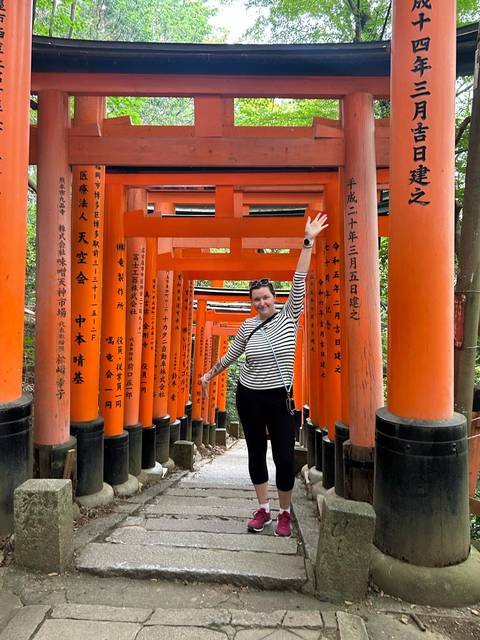       Person standing among traditional orange torii gates.
  