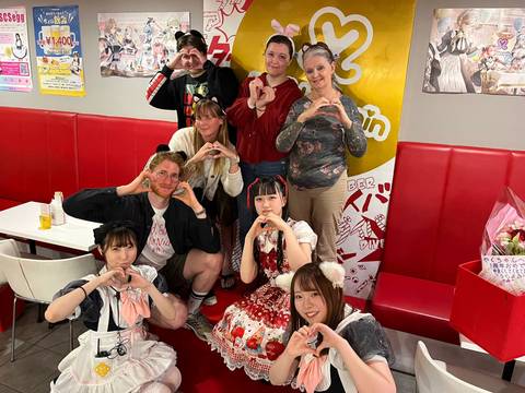       Group of people posing in a themed cafe with costumes.
  