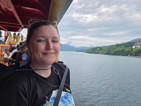       Person on a boat with a scenic water and mountain view.
  