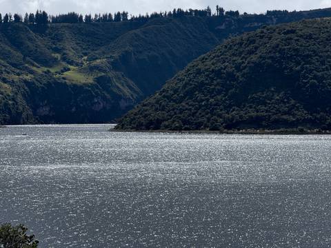       A lake with surrounding hills and glistening water.
  