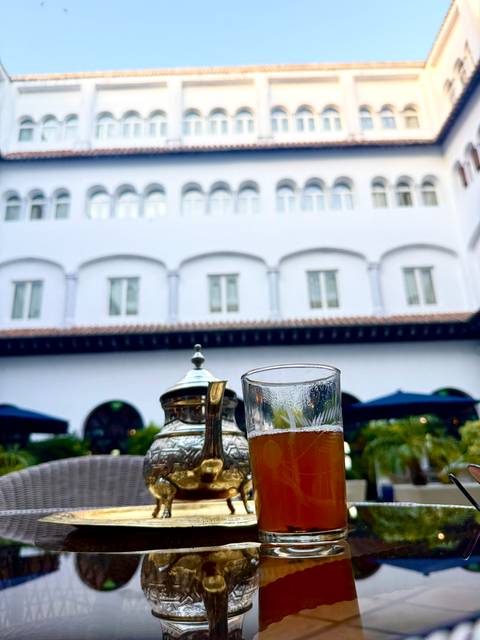 Tea set and a glass of tea in front of a traditional building.