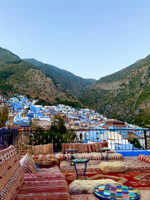 Hilltop view of a town with blue buildings surrounded by rugged terrain.