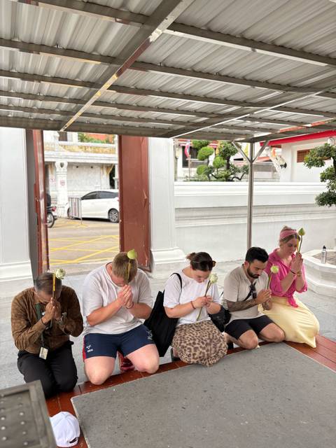 People praying with lotus flowers in a temple.