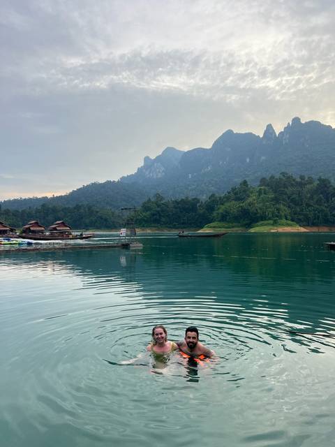 Lake with houses on stilts and forested mountains.