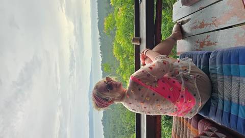       Person relaxing on a balcony with a scenic view.
  