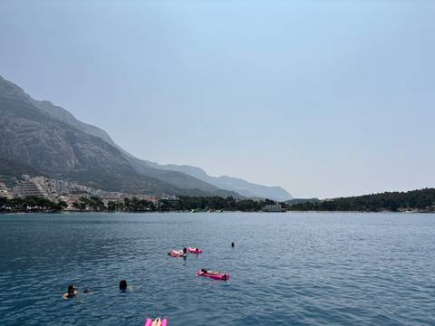 Coastal landscape with calm waters and people floating on inflatables.