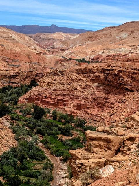 Ancient village with red rocks and green vegetation.