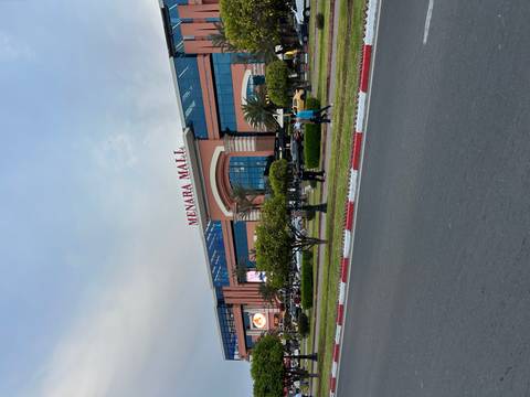 Shopping mall entrance with people and cars outside.