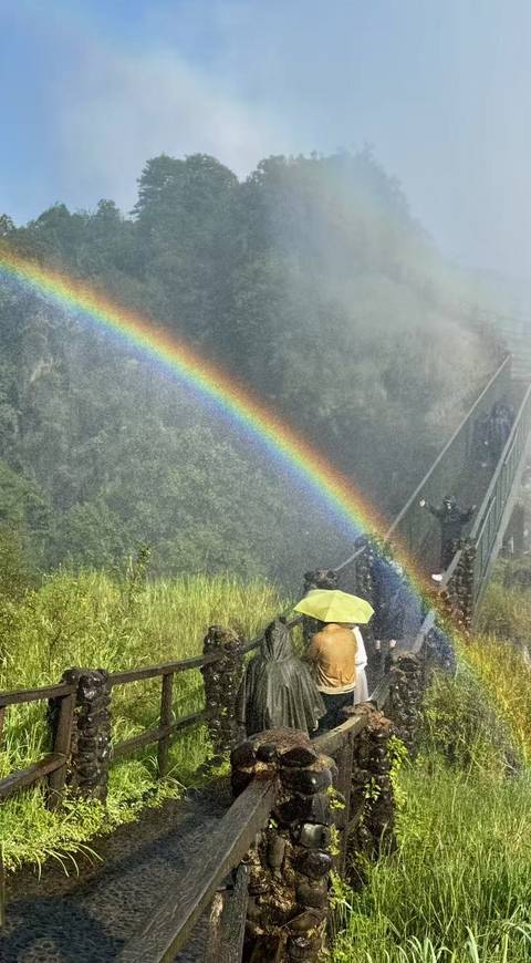 People walking on a bridge with a rainbow in a misty environment.