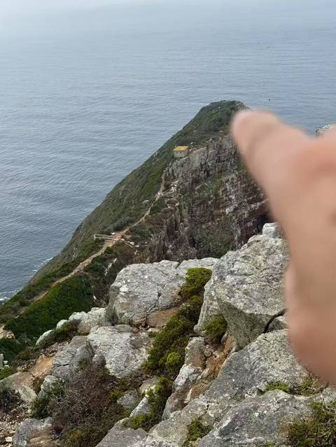       Rocky cliffside with a walking path and ocean view.
  